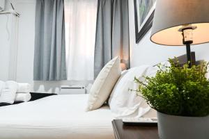 um quarto com uma cama branca e uma mesa com um candeeiro em For You Rentals Acogedor Apartamento de Dos Dormitorios en Madrid HDB12 em Madri
