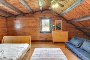 a bedroom with wooden walls and a bed and a couch at Lock Haven Cabin with Wood Stove and Mountain View! in Lock Haven