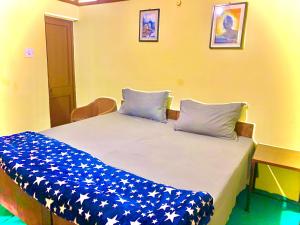 a bed with blue and white sheets and pillows at The Kashi Baba Homestay in Dharamshala +6 photos