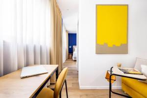 a dining room with a table and a yellow couch at Sirkin 16 Hotel - Autonomous hotel in Giv‘atayim