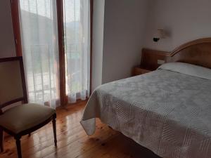 1 dormitorio con 1 cama, 1 silla y ventanas en CAL RAMUNDAINA en Queralbs