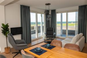 ein Wohnzimmer mit einem Tisch, Stühlen und einem TV in der Unterkunft Residentie Oosterschelde in Sint Philipsland