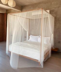 a bedroom with a canopy bed with white sheets and pillows at BASED - Mersing in Mersing