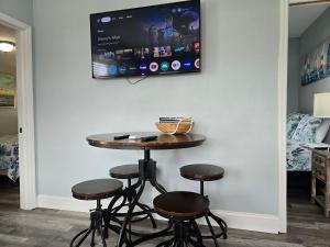 a room with a table and stools with a tv on the wall at Iguana Updated Home By Large Imperial River 1 Mi to Beach in Bonita Springs