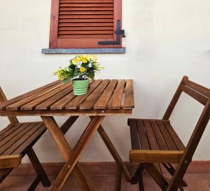 einen Holztisch mit einer Vase aus Blumen und zwei Stühlen in der Unterkunft Midori House Florence in Campi Bisenzio