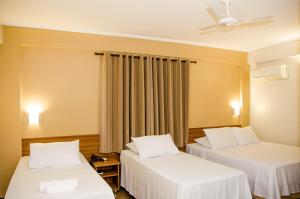 um quarto com 2 camas e uma ventoinha de tecto em Hotel Zé Maria em Pouso Alegre