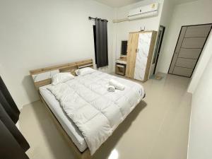 a bedroom with a large bed with white sheets at บ้านพูลทรัพย์วิลเลจ POONSUB VILLAGe in Ban Na Charoen