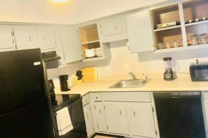 een keuken met witte kasten en een zwarte koelkast bij The Urban Oasis in Clarksville