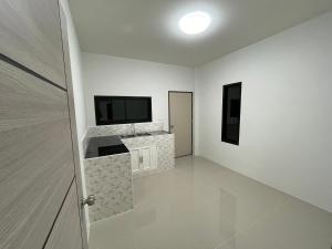 a room with a television and a white wall at บ้านพูลทรัพย์วิลเลจ POONSUB VILLAGe in Ban Na Charoen