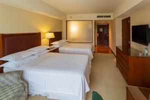 a hotel room with two beds and a flat screen tv at Sheraton Mendoza Hotel in Mendoza