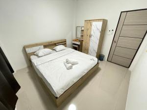 a bedroom with a large bed with white sheets at บ้านพูลทรัพย์วิลเลจ POONSUB VILLAGe in Ban Na Charoen +3 photos