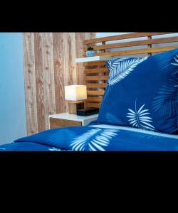 a bed with blue pillows with a wooden head board at Studio cosy gold Douala Cameroon in Douala