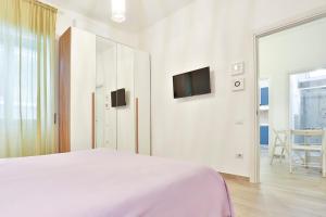 - une chambre blanche avec un lit et une télévision dans l'établissement Angolo Marconi Seaside Apartment, à Salerne