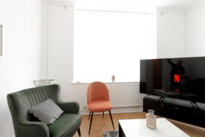 a living room with a green chair and a television at Liverpool Delight: Cosy Single Room in Liverpool