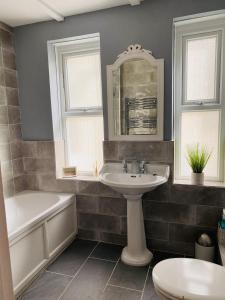 een badkamer met een wastafel, een bad en een spiegel bij Ocean Terrace, Ilfracombe Spacious, Sleeps 8, Stunning Sea Views, Parking, Garden, Pet Friendly in Ilfracombe