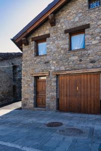 ein Steinhaus mit einer großen Holzgarage in der Unterkunft Excenex Apartment in Aosta