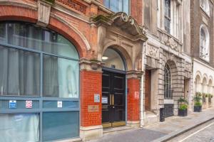 een bakstenen gebouw met een gewelfde deuropening in een straat bij Bank/Monument apartment in Londen