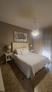 een slaapkamer met een groot wit bed en een kroonluchter bij Casa Bignonia in Salteras