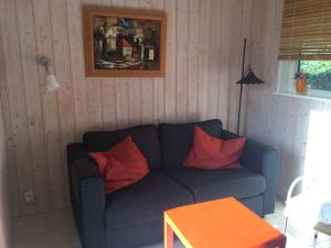 een woonkamer met een blauwe bank en rode kussens bij Comfortable Cottage by the Beach in Egmond in Rinnegom