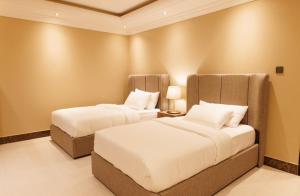 two beds in a hotel room with white pillows at Luxury apartments Alkhobar in Al Khobar