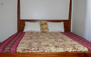 a bed with a wooden headboard and two pillows at Kalunga Holiday Home in Banda