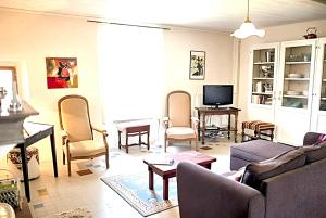 sala de estar con sofá, sillas y TV en Maison de 2 chambres avec piscine partagee jardin clos et wifi a Massaguel, en Massaguel