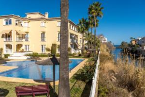 a building with a pool and a palm tree at Casita Bonita - with private garden near beach in Jávea in Jávea