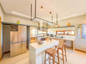 a kitchen with a large island with bar stools at Maruwá - Villa Deluxe 30 in Mata de Sao Joao