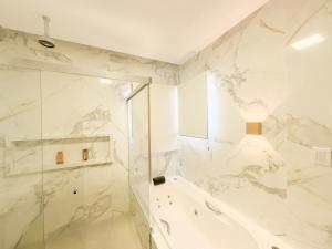 a white bathroom with a shower and a glass at Maruwá - Villa Deluxe 30 in Mata de Sao Joao