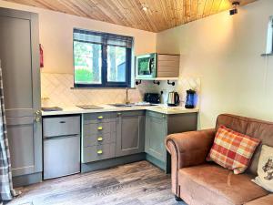een keuken met blauwe kasten en een bank in een kamer bij Arc Pod-HotTub-HuntersMoon-Warminster-Bath in Warminster