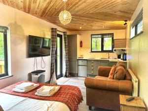 a bedroom with a bed and a couch and a kitchen at Arc Pod-HotTub-HuntersMoon-Warminster-Bath in Warminster