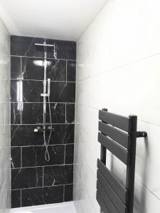 een badkamer met een zwart betegelde muur en een douche bij Arc Pod-HotTub-HuntersMoon-Warminster-Bath in Warminster