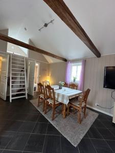 een eetkamer met een tafel en stoelen en een televisie bij Lite hus til leie sommeren 2024 in Arendal