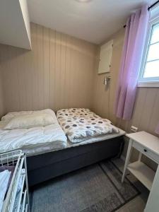 a small bedroom with a bed and a window at Lite hus til leie sommeren 2024 in Arendal
