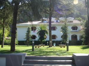 un grande edificio bianco con alberi di fronte di Villaggio Turistico La Mantinera - Hotel a Praia a Mare