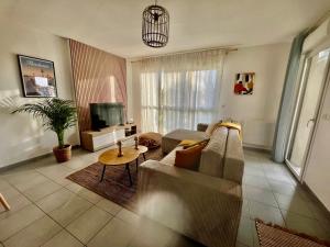 a living room with a couch and a tv at Appart Cosy 6 personnes in Floirac