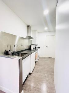 una cocina con armarios blancos y fregadero en Apartamentos dos Habs Madrid Urgel en Madrid