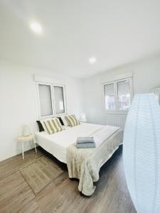 a white bedroom with a large bed and two windows at Apartamentos dos Habs Madrid Urgel in Madrid