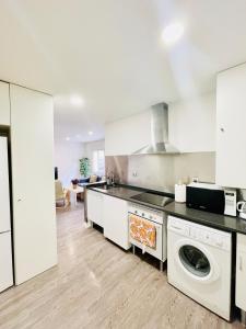 cocina con armarios blancos, lavadora y secadora en Apartamentos dos Habs Madrid Urgel en Madrid