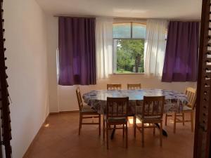 a dining room with a table and chairs with purple curtains at Apartments Milan in Peroj