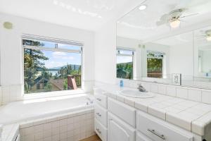 baño blanco con bañera, lavabo y ventana en WINTERFELL LAKEVIEW - EV Charger - Walk to Slopes/Lake, en Big Bear Lake