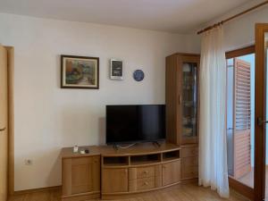 a living room with a flat screen tv on a wooden cabinet at Apartments Milan in Peroj