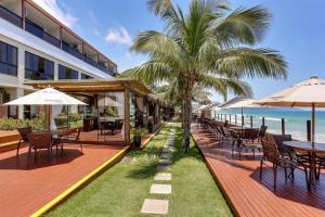 una terraza del hotel con mesas, sillas y una palmera en Flat Pietra, en Florianópolis