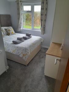 1 dormitorio con cama y ventana en Devon Hills Holiday Park luxury timber lodge pet friendly with hot tub 2 to 6 guests, en Paignton