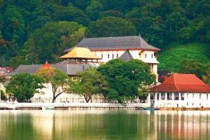a large building next to a large body of water at Sobasee Deluxe Bungalow in Kandy