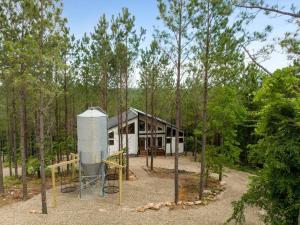 una casa en el bosque con una torre de agua en New Cabin w Hot Tub + Views Sleeps 12, en Broken Bow