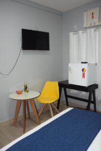 uma sala de estar com uma mesa e uma cadeira amarela em Hostel Cidade Velha em Belém