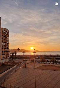 a sunset over a beach with a building and the ocean at Empuriabrava Vue Mer in Empuriabrava