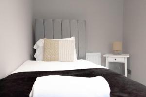 a bedroom with a white bed with a gray headboard at Castlemilk House in Glasgow