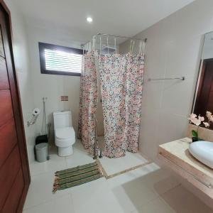 y baño con aseo y cortina de ducha. en Pousada Aconchego de Genipabu en Genipabu